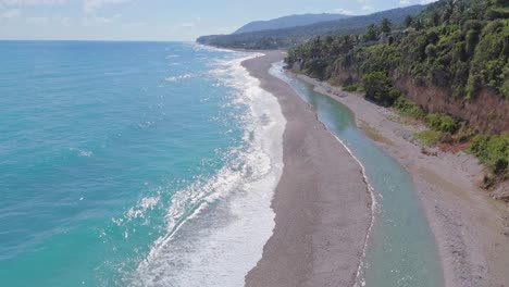 aerial forward flight along beach and shoreline of los patos in barahona during sunny day, dominican republic