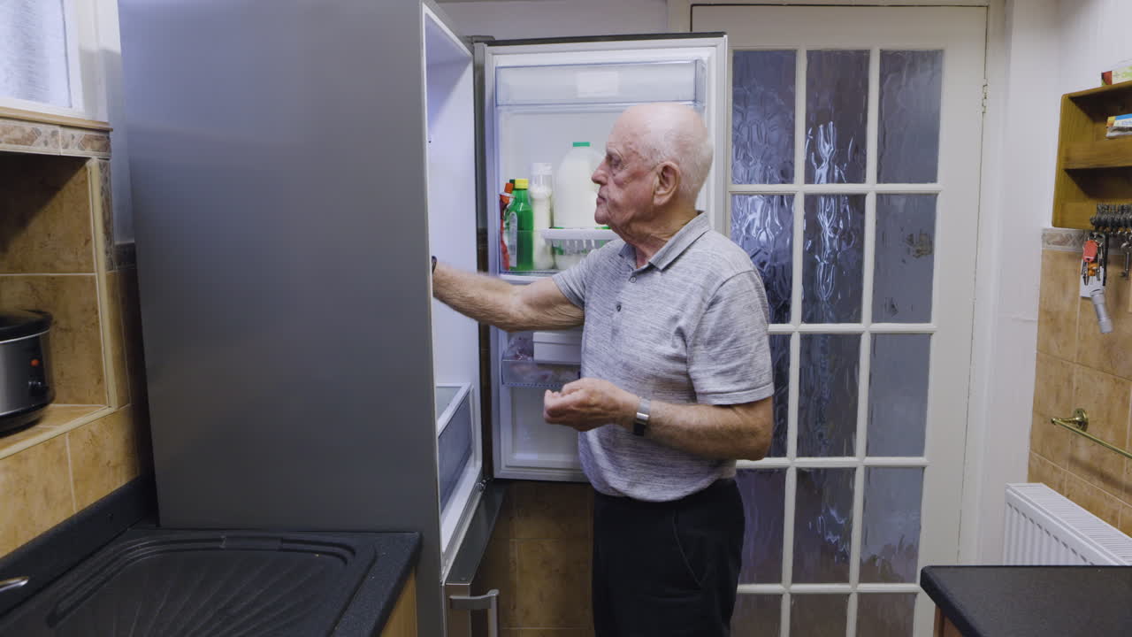 Elderly man looking in refrigerator
