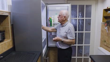 elderly man looking in refrigerator