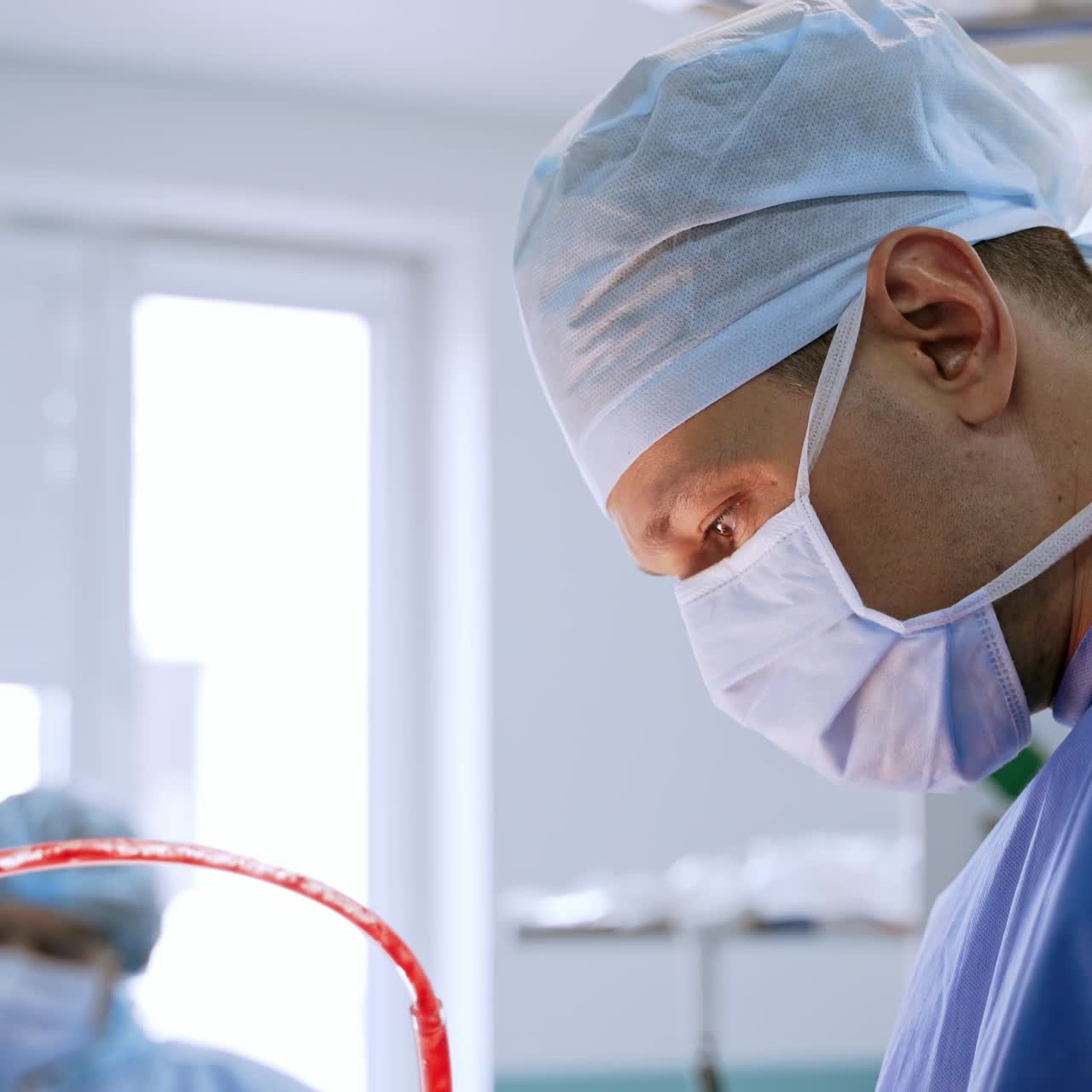 Surgeon during the operation to a patient. Medical tubes with blood in operating process in surgery room. Professional doctor operates in clinic.