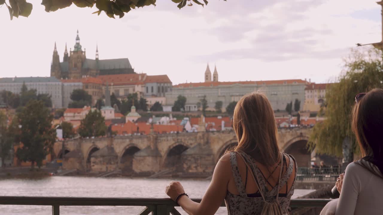 Due ragazze guardano il Castello di Praga e il Ponte Carlo, giornata di sole e vento, Repubblica Ceca