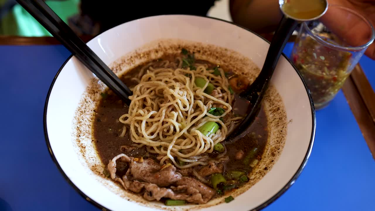 Aggiungere condimento a una ciotola di deliziosa zuppa di noodle asiatici