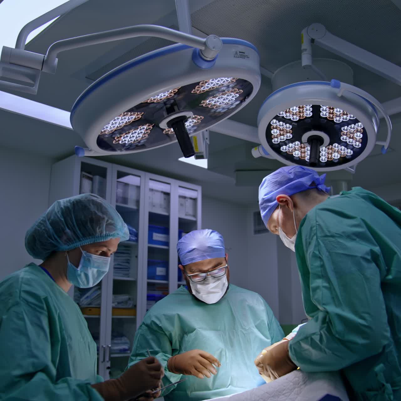 Surgery on foot performed by two surgeons. Doctor cleans the operated area with sponge. Nurse passes another sponge with iodine