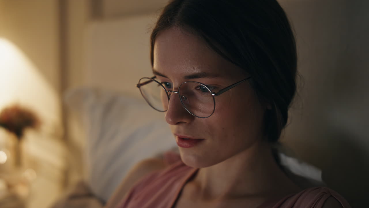 Closeup focused girl working home at night. Serious woman freelancer in glasses