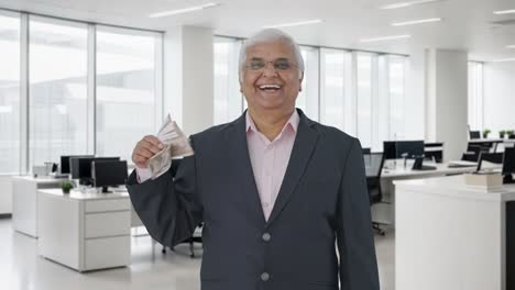 el gerente senior indio feliz usando el dinero como fan