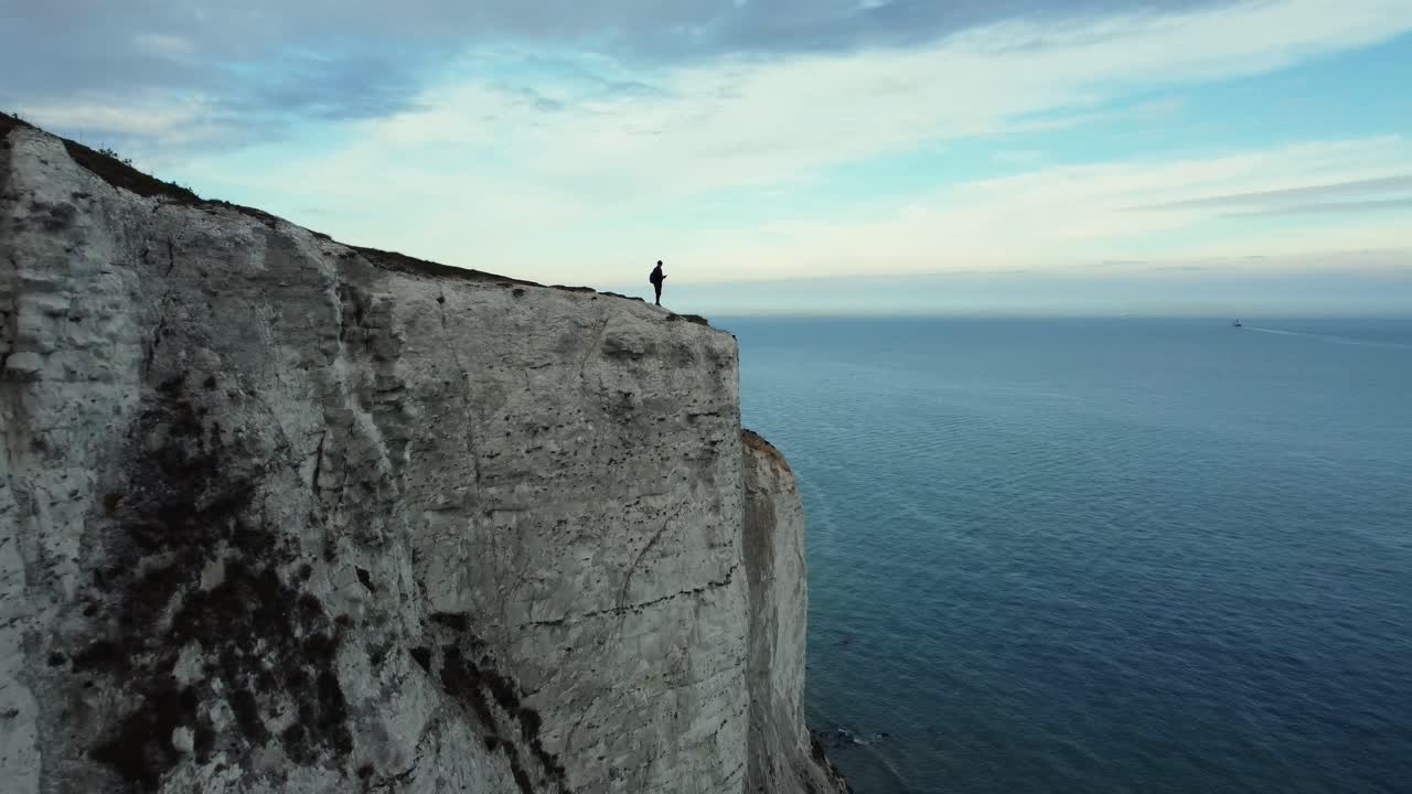 Man Standing on White Cliffs Overlooking the Sea