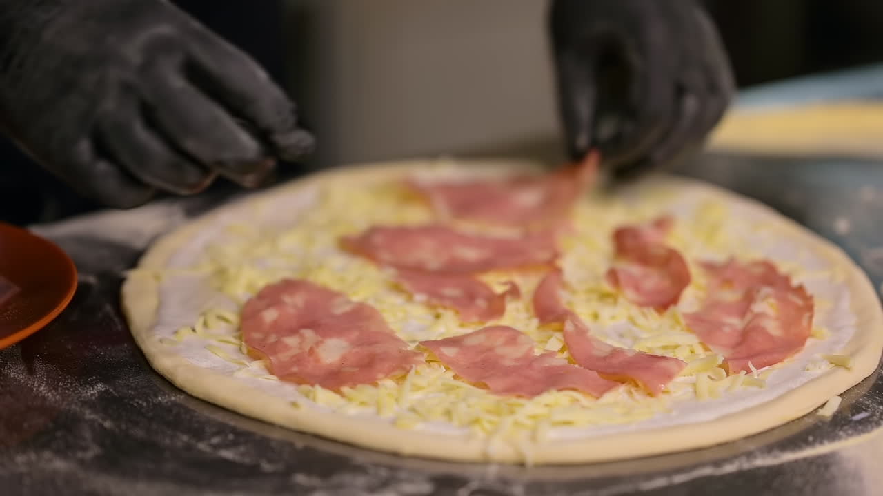Processo di preparazione della pizza al ristorante. Processo di preparazione della pizza tradizionale italiana. Lo chef aggiunge prosciutto e formaggio.