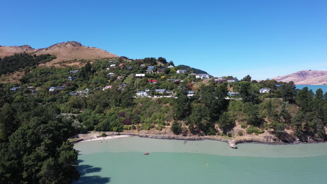 Drone shot over the sea, past moored boats, revealing bay