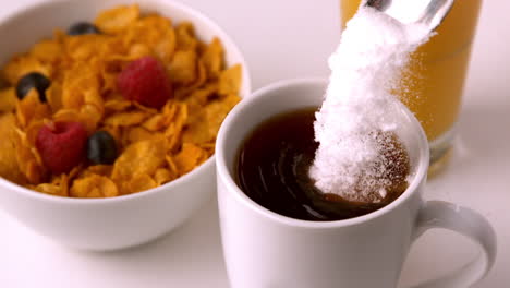 sugar pouring into mug at breakfast table