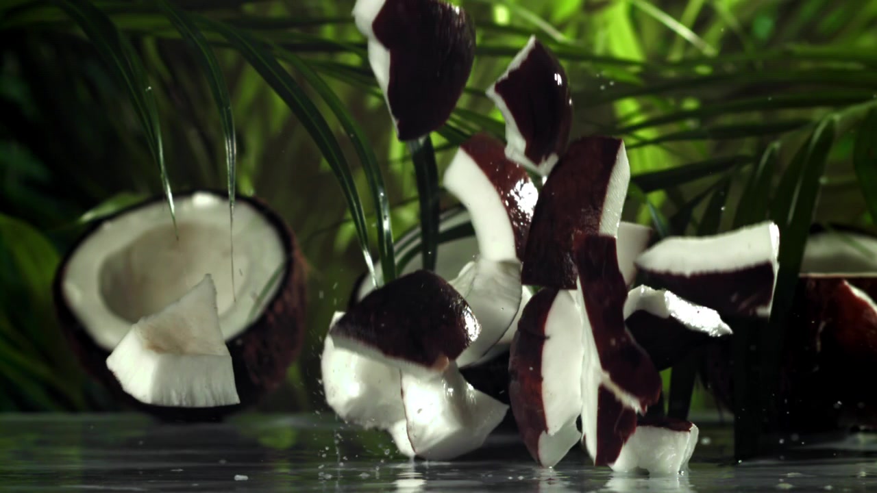 Fresh Coconut Chunks Falling with Water Splashes Against Tropical Background