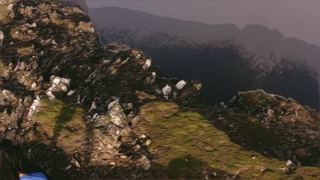 Man-with-long-dreads-stands-at-edge-of-cliff