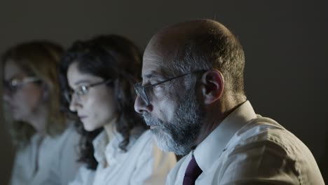 colegas serios trabajando en la oficina oscura