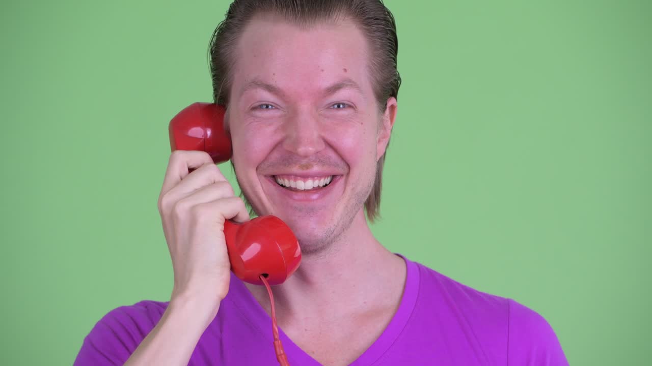 녹색 배경 에 웃고 전화 로 이야기 하는 젊은 남자 의  을 확대