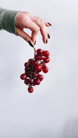 hand holding a bunch of red grapes