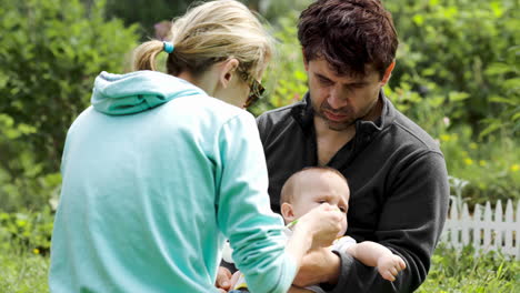 young parents feeding a baby boy outdoor