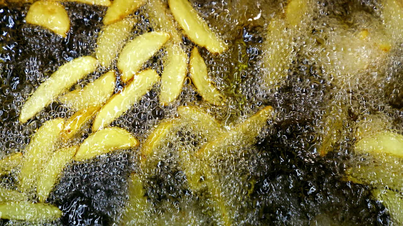 Potatoes are frying in hot boiling oil. French fries fried in restaurant. Video from the top on cooked potatoes.
