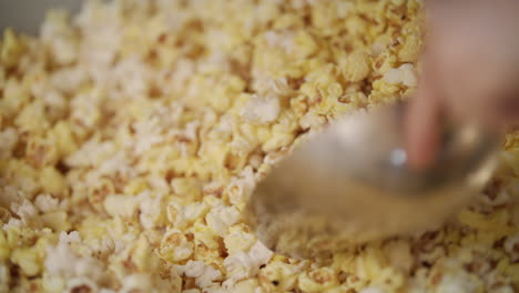 mano humana vertiendo palomitas de maíz listas de la máquina de palomitas de maíz por cuchara