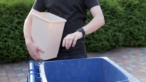 caucasian male taking out trash sorting plastic bottles for recycling