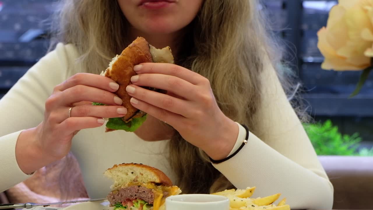 Woman eating a burger with fries at a restaurant