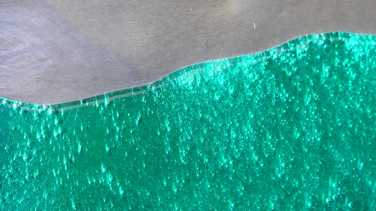 gotas de líquido verde esmeralda en la superficie del metal