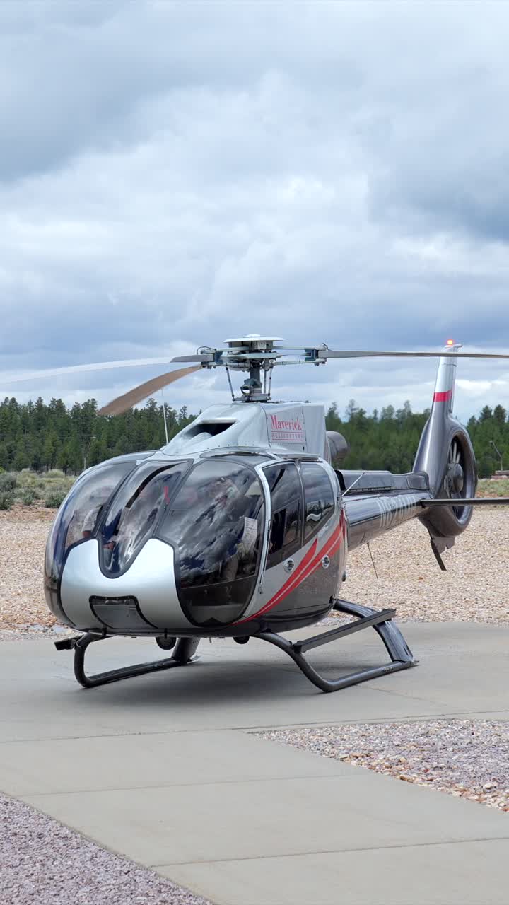 Hélicoptère argenté avec des pales de rotor en rotation sur un héliport