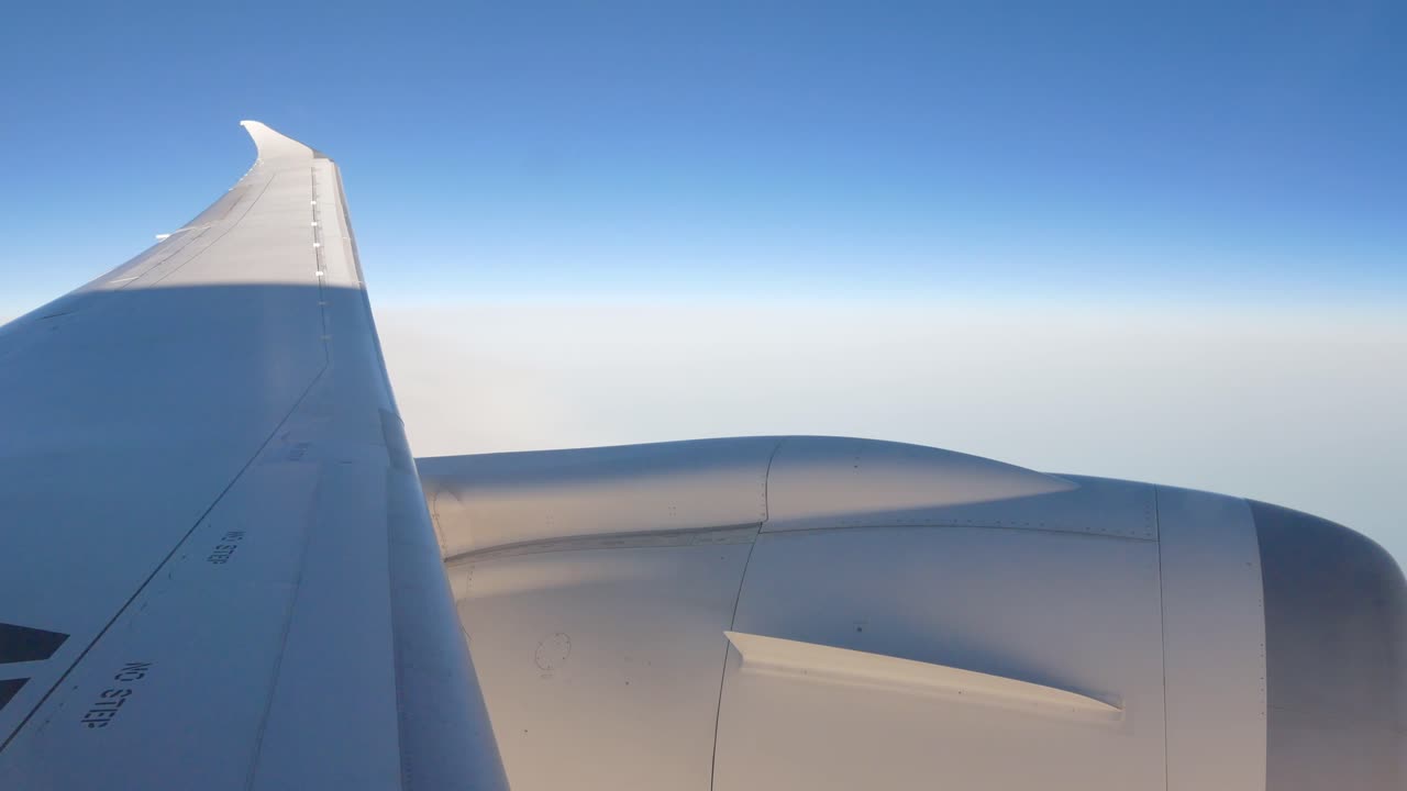 View from inside the plane cabin while flying on 35,000 feet height with full thrust engine - see plane's wing and engine from business class section