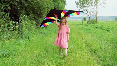 Front-view-of-little-girl-playing-with-a-kite-in-the-park-on-a-sunny-day