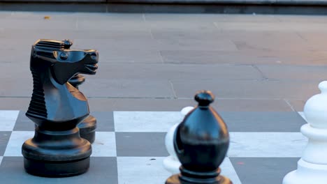 люди проходят мимо больших открытых шахматных фигур