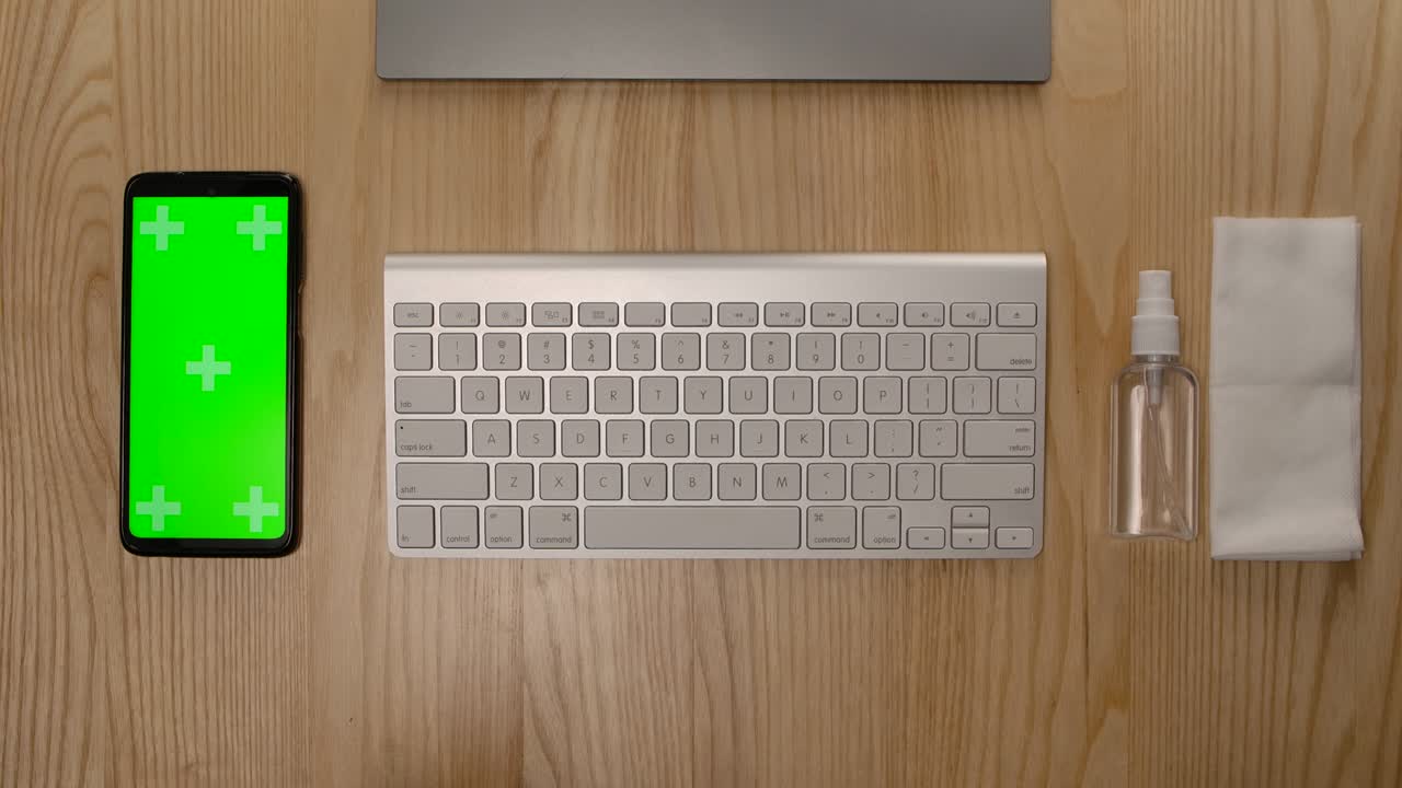vista superior del escritorio en casa o en la oficina. teclado de computadora blanco, antiséptico con una servilleta y teléfono inteligente con pantalla verde y tecla de croma con posición vertical de la pantalla. cerrar. cámara lenta