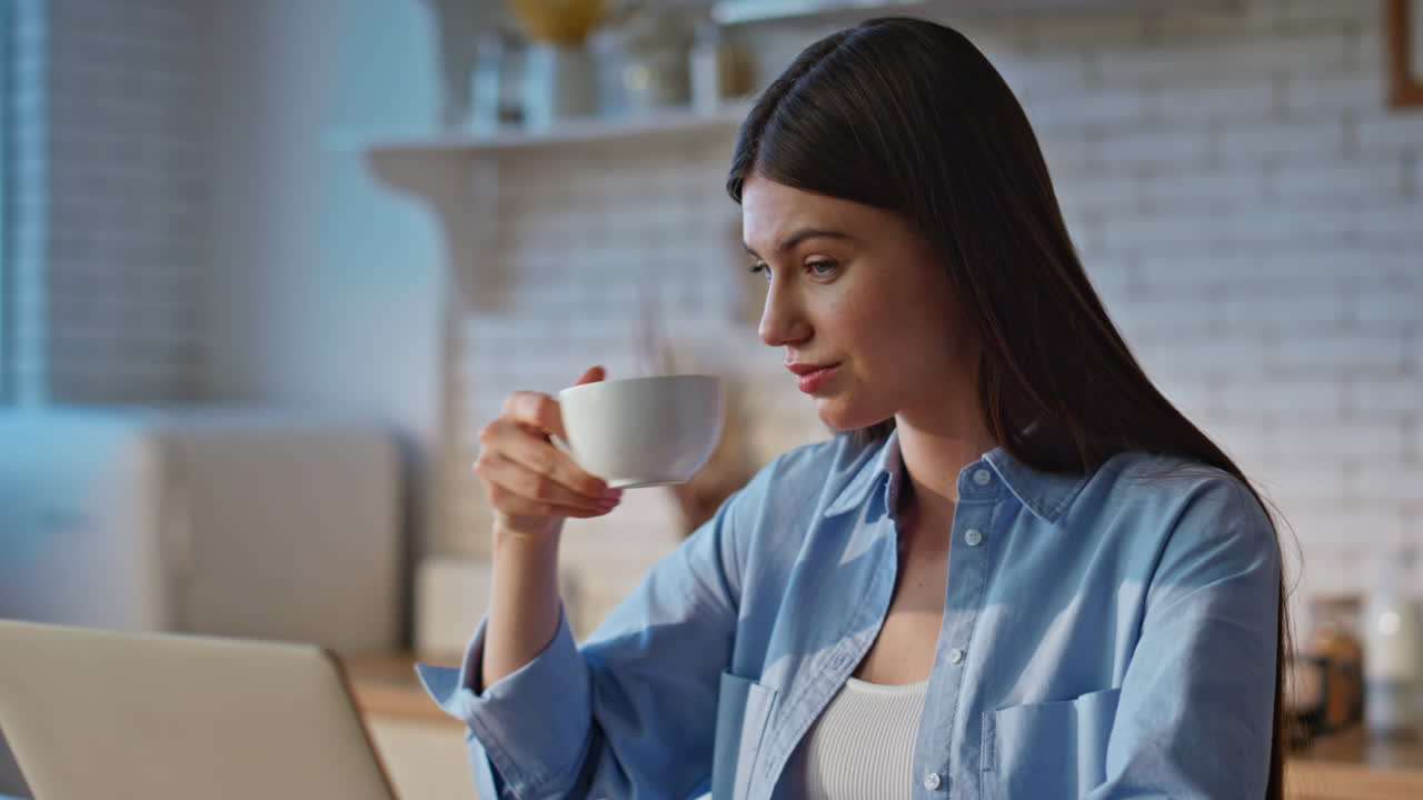 Lady freelancer working laptop at kitchen closeup. Smiling woman drinking tea