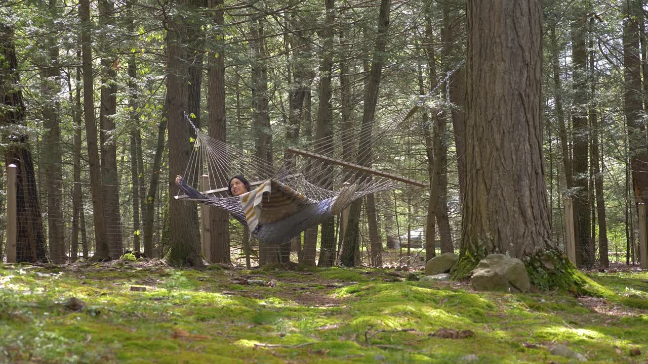 cómoda mujer puertorriqueña balanceándose en una hamaca en el bosque disfrutando de la vida escapando