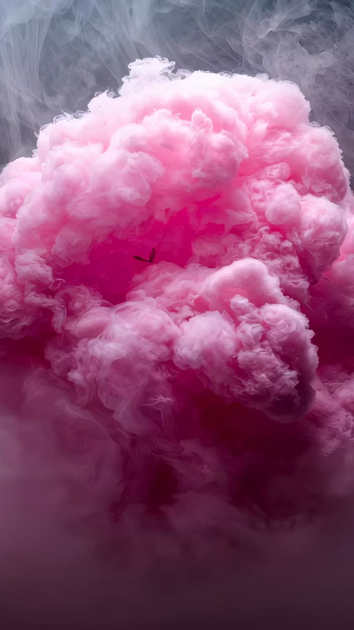 Vertical video: Expanding large pink plume inflating after dye drop in studio tank, with gray mist