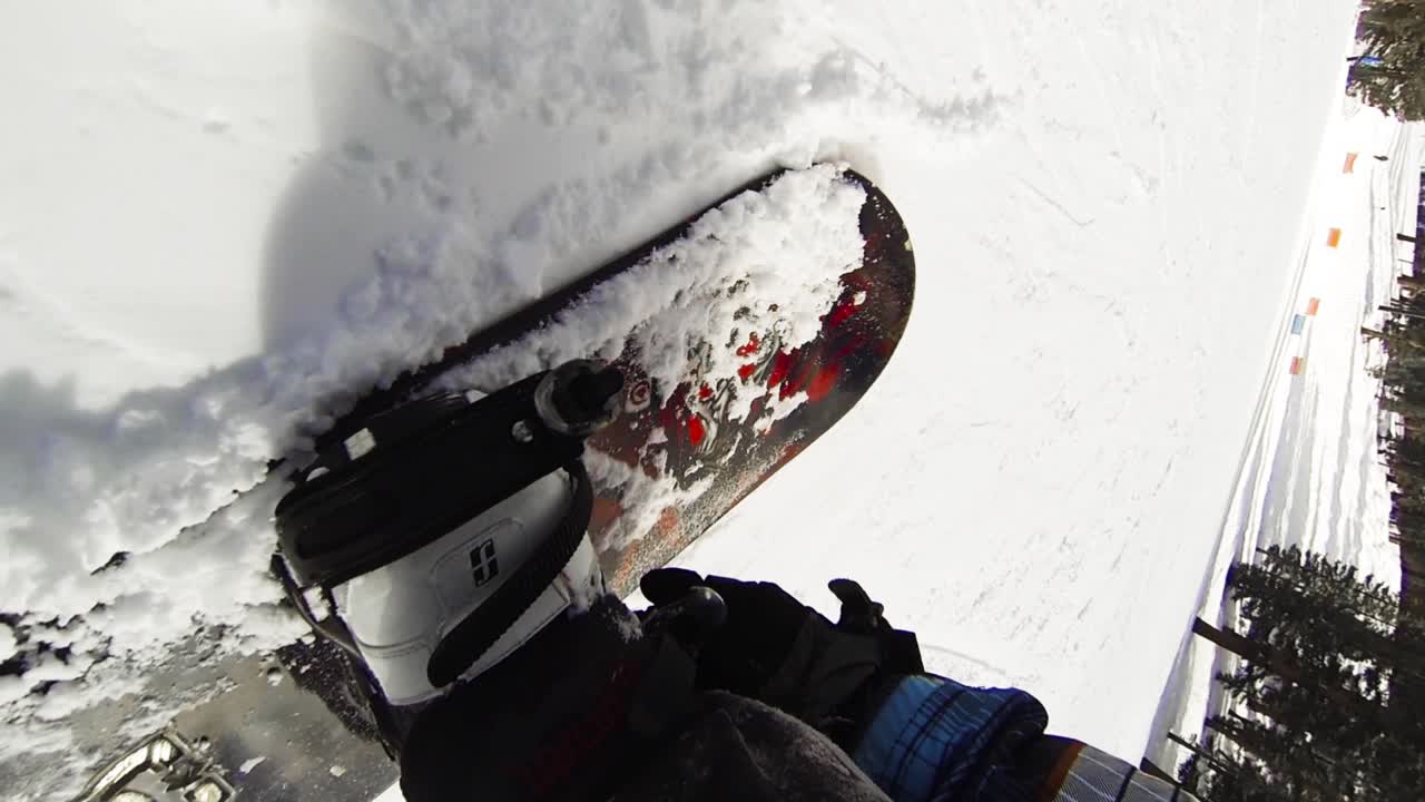 POV, close up of a snowboarder slides to stop releases bindings.