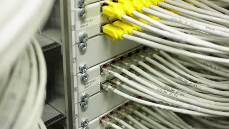 Close-up-white-wires-connected-to-the-internet-in-a-server-room,-tilt-up