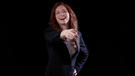 a caucasian businesswoman pointing at the camera and laughing