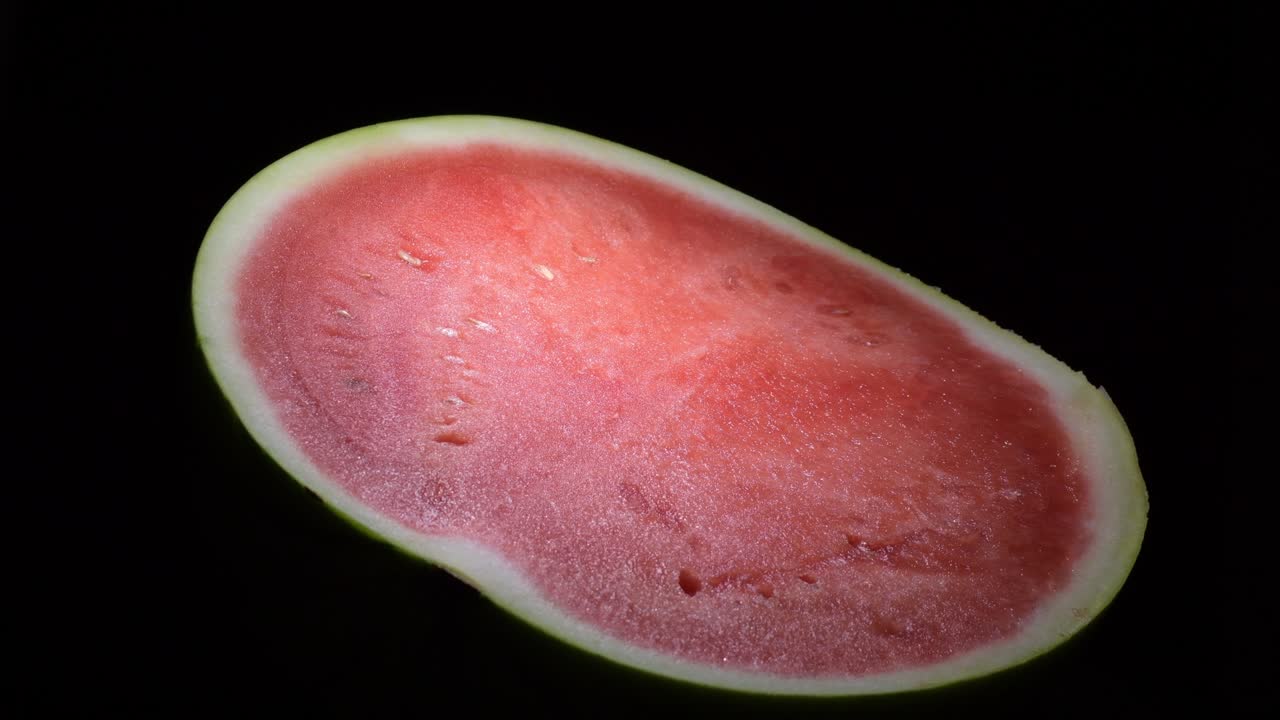 sandía cortada por la mitad girando sobre fondo negro