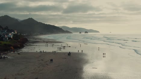 4k aerial people walking on the beach on cloudy day drone dolly in + jib down