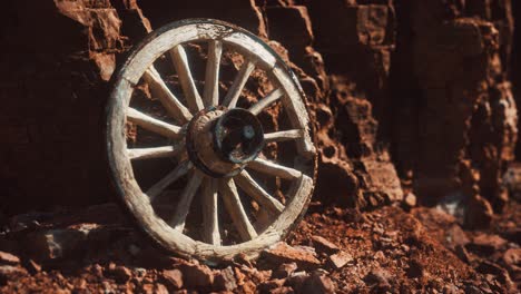 old wooden cart wheel on stone rocks