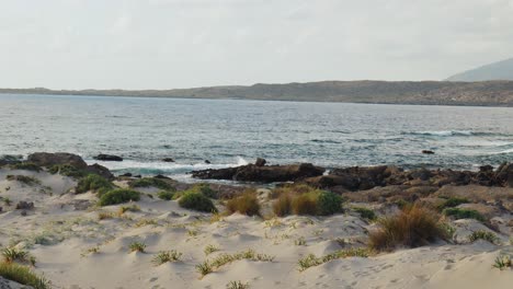 Wellen,-Die-An-Wilder-Felsiger-Küste-Krachen,-Elafonissi-inselstrand-Auf-Der-Insel-Kreta-Mit-Azurblauem-Klarem-Wasser,-Grasbewachsenen-Sanddünen-Neben-Dem-Meer,-Griechenland