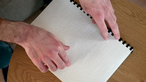 Vista-Superior-De-Un-Hombre-Irreconocible-Leyendo-Un-Libro-En-Braille-En-Casa