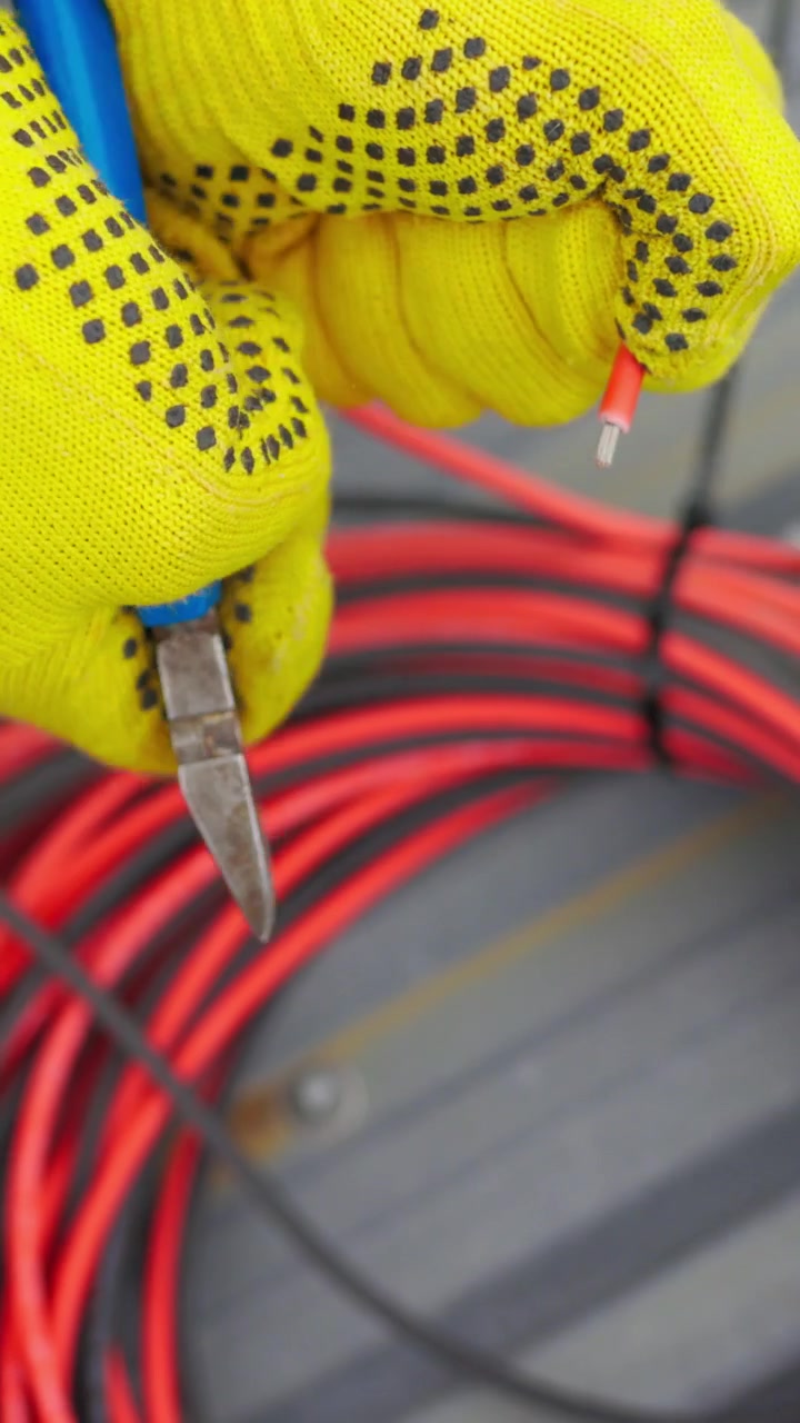 A gloved hand holds a cut wire highlighting electrical work and safety vertical video