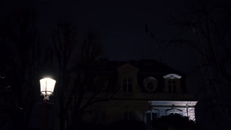 Low-Angle-Aufnahme-Eines-Alten,-Gepflegten-Bungalows-Mit-Straßenlaternen-Im-Vordergrund-Bei-Nacht