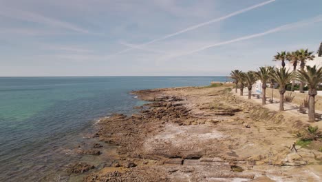 Fy-over-rocky-shores-of-Praia-da-Luz-beach,-Lagos,-Algarve