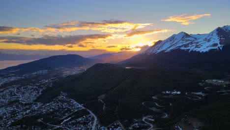 drone shot flying over ushuaia, argentina towards a dramatic sunset in the andes mountains