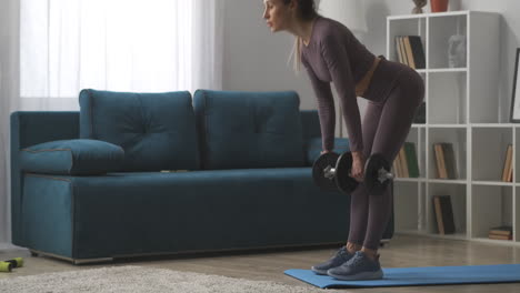 young-blonde-is-training-with-dumbbells-doing-tilts-in-living-room-fitness-at-home-healthy-lifestyle-and-wellness-power-training