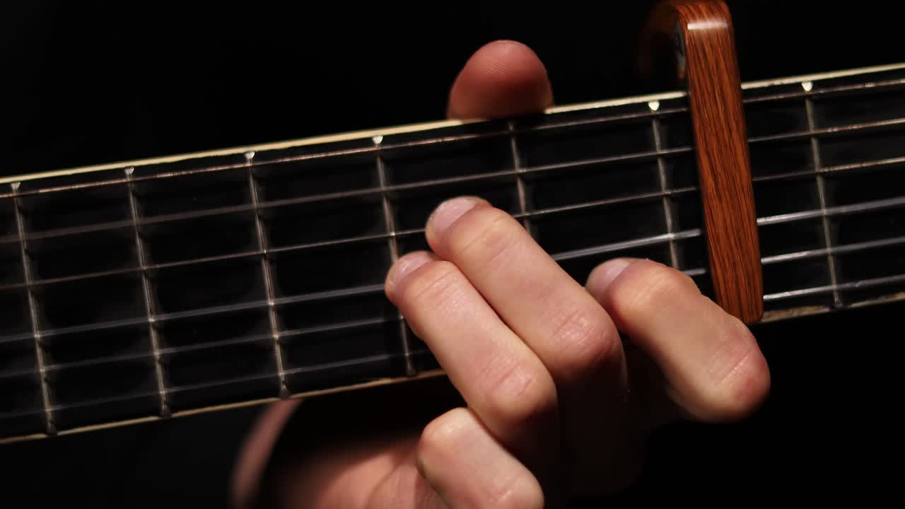 toma detallada de la mano del guitarrista en el cuello de la guitarra mientras toca la guitarra