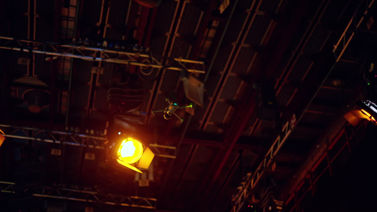 Drone flying and filming near flashing studio lights equipment on the ceiling of a TV set