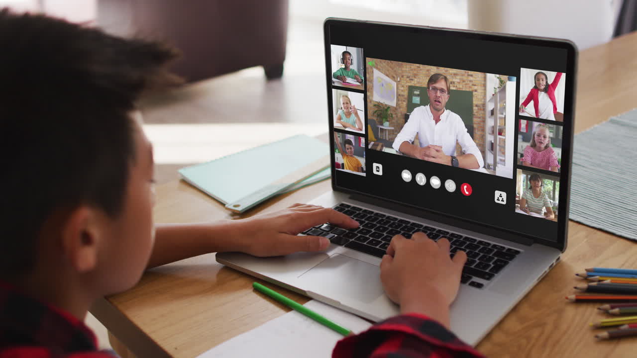 Schuljunge nutzt Laptop für Online-Unterricht zu Hause, mit einer vielfältigen Lehrkraft und Klasse auf dem Bildschirm.