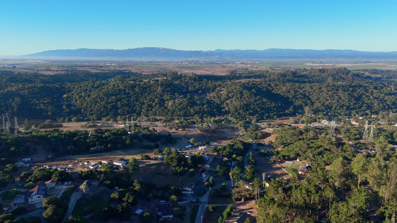 Wide forested valley with scattered homes and mountains in Salinas Valley, California