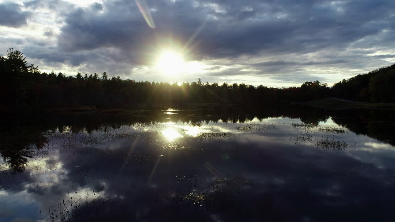 Slow moving drone shot of a sunset over a calm mirror reflective lake